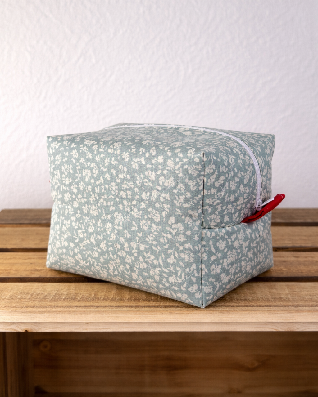 Cube-shaped fabric pouch with a floral pattern on a wooden surface