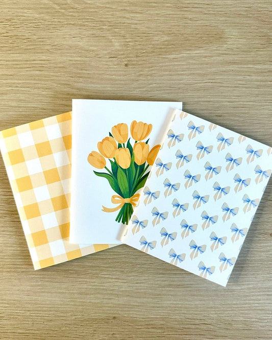 Three greeting cards with different designs on a wooden surface